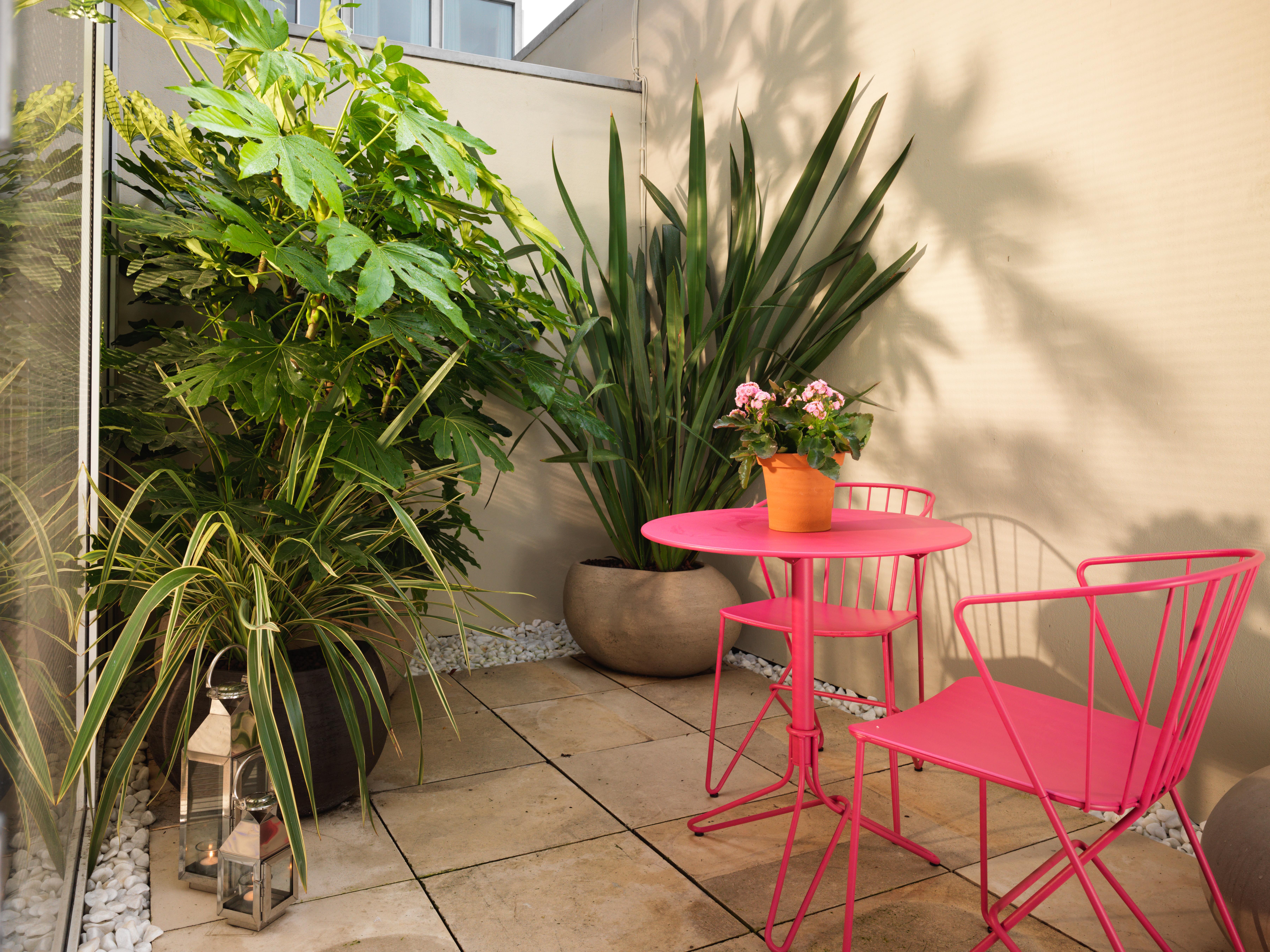 St Martins Lane London Hotel Kültér fotó The photo shows a small outdoor area or balcony with a cozy setup. In the center, there is a round pink table with two matching pink chairs. On the table, there is a potted plant with pink flowers. Surrounding the table are various plants, including 