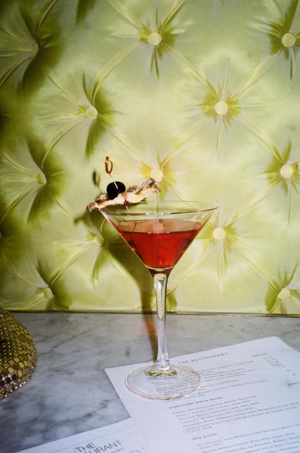 St Martins Lane London Hotel Kültér fotó The photo depicts a cocktail served in a classic martini glass. The drink appears to be a reddish color, likely indicating it contains ingredients like cranberry or grenadine. Garnishing the drink is a shrimp with a cocktail skewer, and there are two