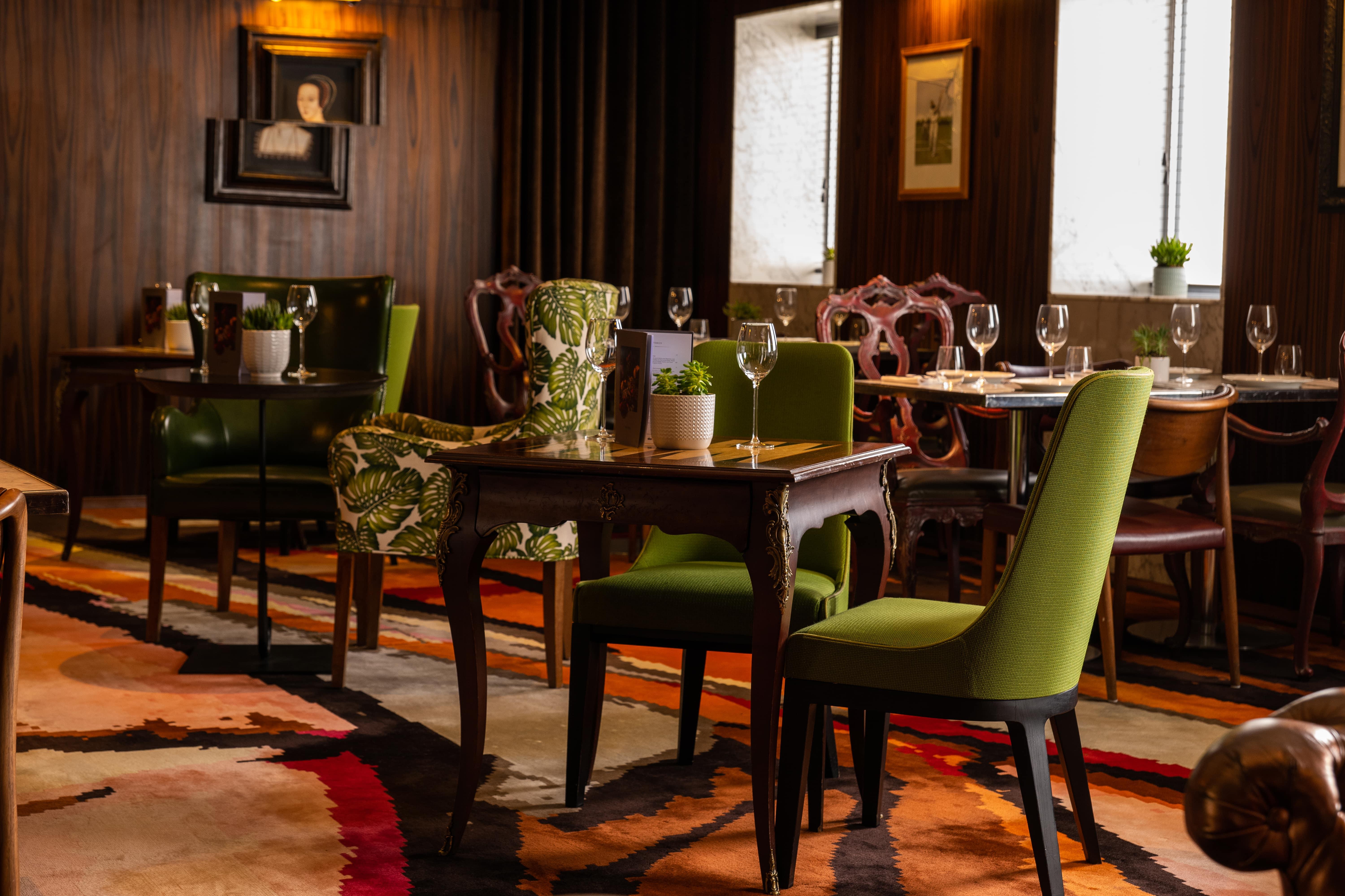 St Martins Lane London Hotel Kültér fotó The image depicts an elegant dining area with a blend of classic and contemporary design elements. There are several tables arranged neatly, each accompanied by stylish chairs. Some chairs have vibrant green upholstery and unique patterns, while othe