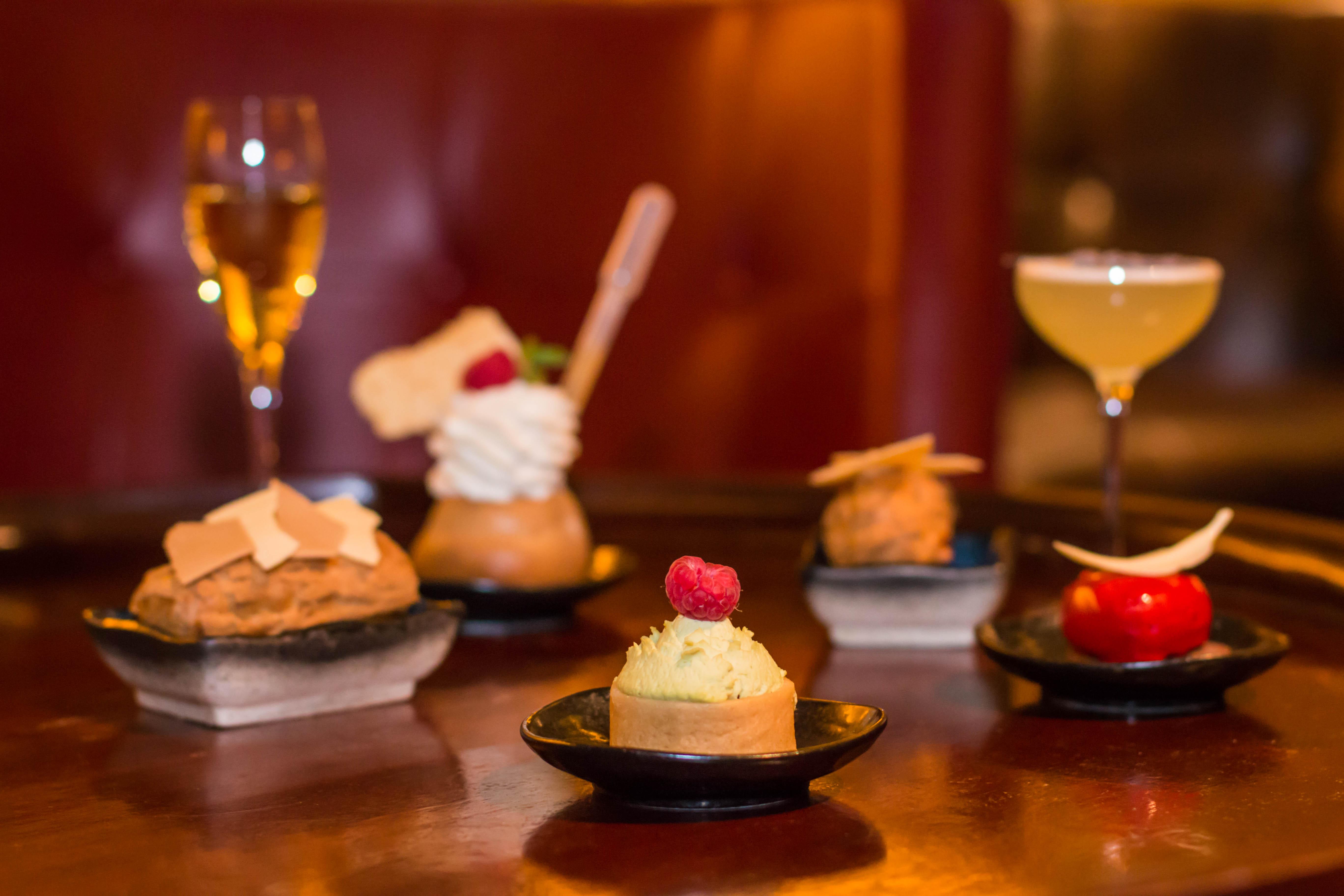 St Martins Lane London Hotel Kültér fotó The photo showcases a variety of elegantly presented desserts and drinks. In the foreground, there are five small plates, each containing a different dessert. The desserts include a creamy cake topped with a raspberry, a small pastry with a swirl of 
