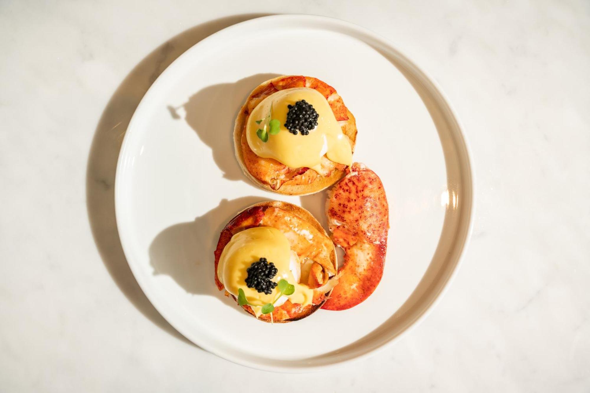 St Martins Lane London Hotel Kültér fotó The photo shows a plate with two servings of a dish that appears to be eggs Benedict. Each serving consists of a toasted English muffin topped with poached eggs, creamy hollandaise sauce, and garnished with black caviar and possibly some green onions