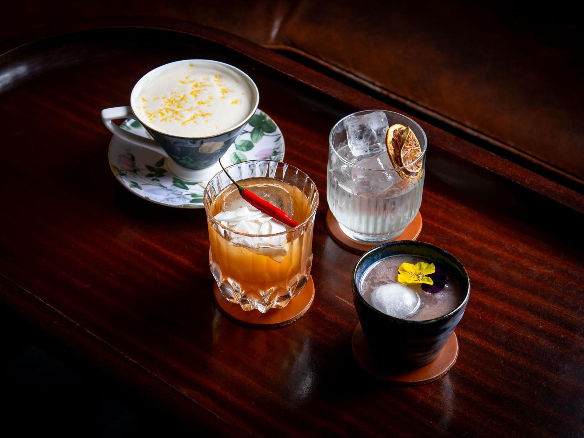 St Martins Lane London Hotel Kültér fotó The photo features a selection of four different drinks arranged on a wooden surface. 

1. On the left, there is a delicate cup with a floral design, containing a creamy beverage topped with what appears to be shavings or sprinkles, possibly coconut 