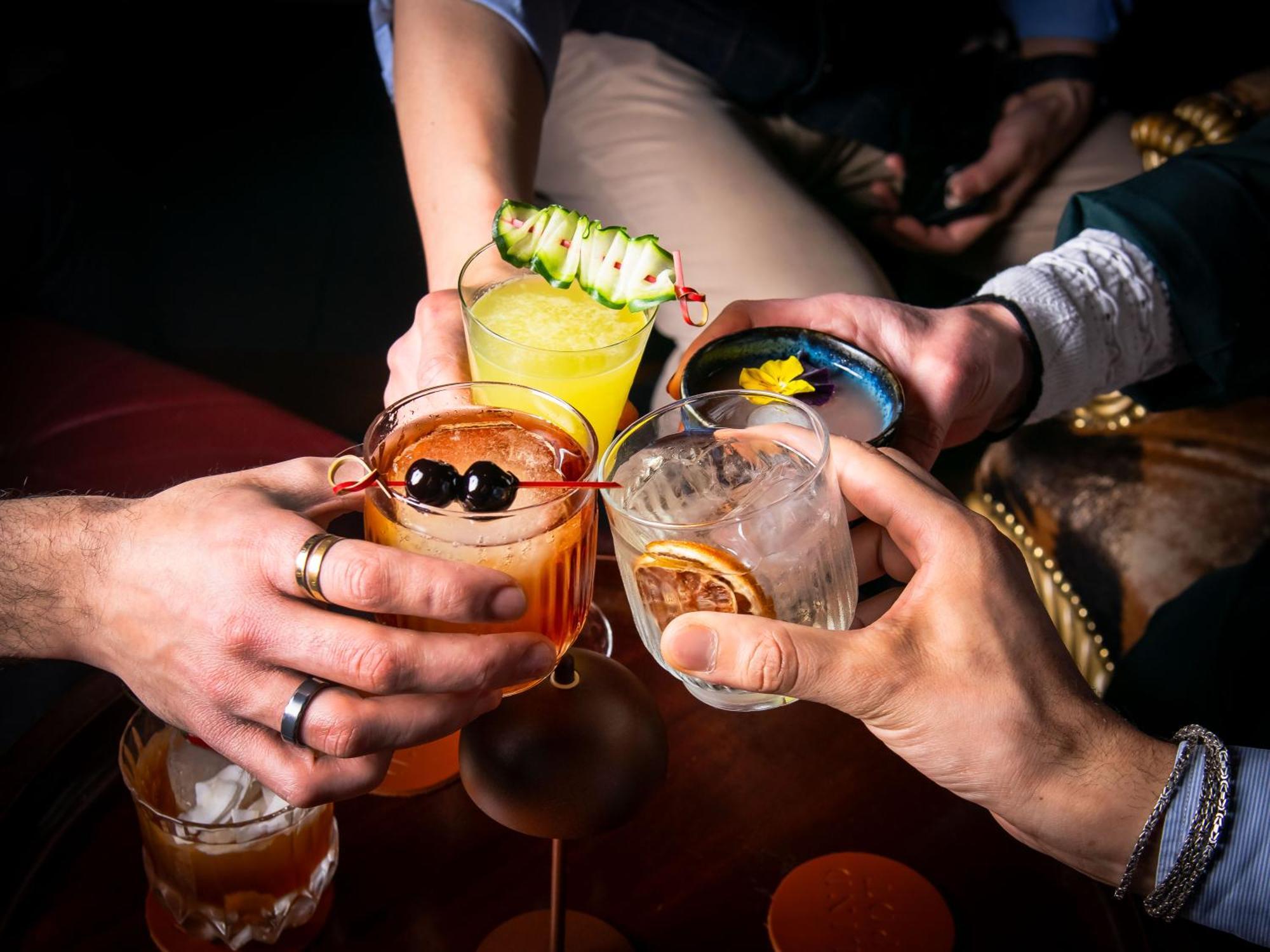 St Martins Lane London Hotel Kültér fotó The photo features a group of hands holding different colorful cocktails, suggesting a celebratory atmosphere. Each drink has distinct garnishes: one has a cucumber slice, another displays a flower, and others feature fruits and decorative elements. 