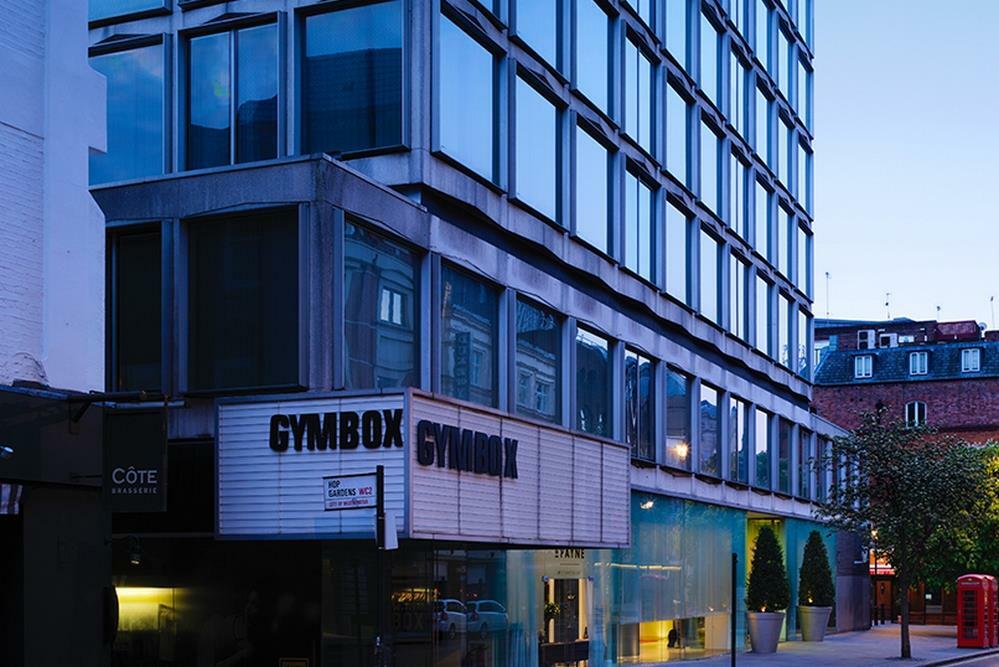 St Martins Lane London Hotel Kültér fotó The image shows a modern building with a distinctive architectural design. The facade features large glass windows, and the lower section includes a sign that reads "GYMBOX." There appears to be some greenery in front of the building, and the scene i